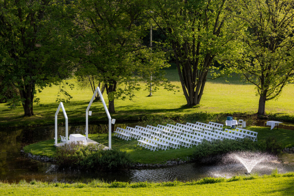 Parc de La Distinction à Joliette - Endroit de célébration extérieure pour  mariage - Double arche - Chaises uniformes blanches - Plan d'eau