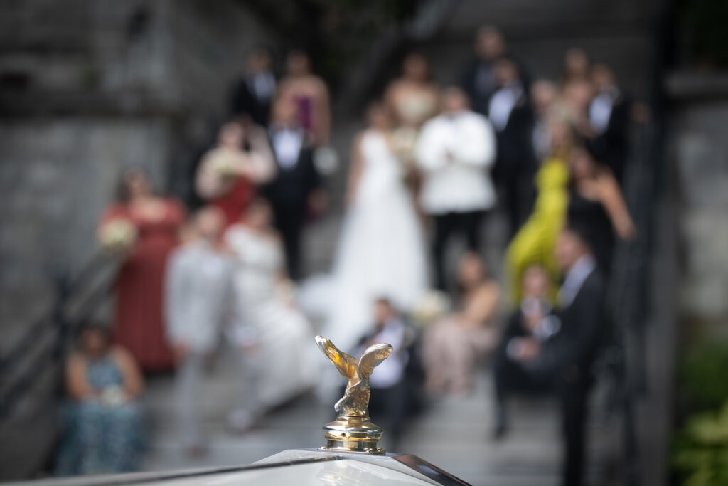 Photo de famille lors d'un mariage avec logo de la Rolls Royce net sur fond flou - Photo prouvant l'avantage d'avoir deux photographes lors d'un mariage.